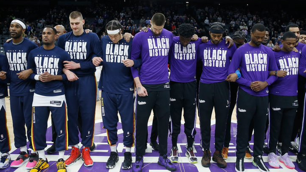 Sacramento Kings and Denver Nuggets players lock arms ahead of their match on 25 February