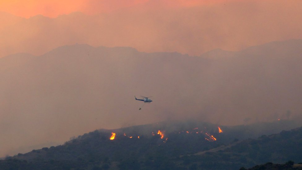 A helicopter flies over a forest fire, in the Larnaca mountain region, Cyprus, 3 July 2021