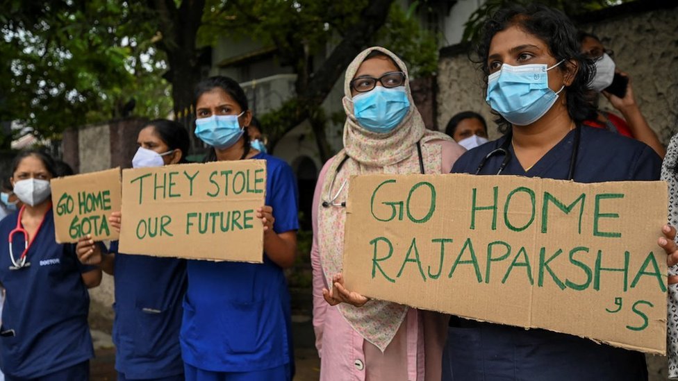Doctors and nurses of the Lady Ridgeway Children's Hospital hold placards with 'Go home Gota', 'They stole our future' and 'Go home Rajapakshas' written on them during a silent demonstration against shortages of medicine in Colombo on 19 April, 2022