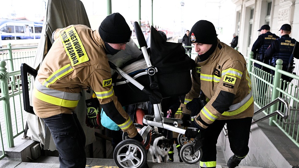 Bomberos polacos llevando un carrito de bebé