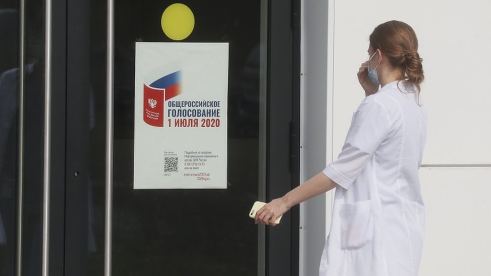Медицинский специалист подходит к входной двери больничного комплекса с наклеенным плакатом