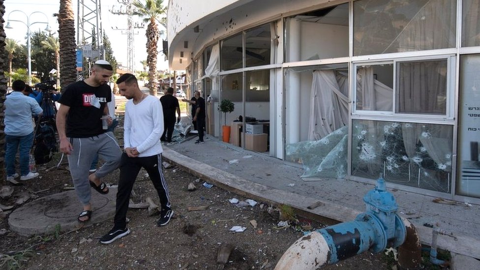 Israelis inspect a building in the northern town of Shlomi that was damaged by rocket fire from Lebanon (6 April 2023)