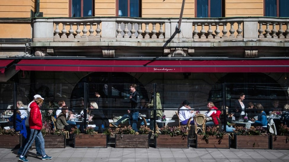 Люди наслаждаются весенней погодой, сидя в ресторане в Стокгольме 15 апреля 2020 года,