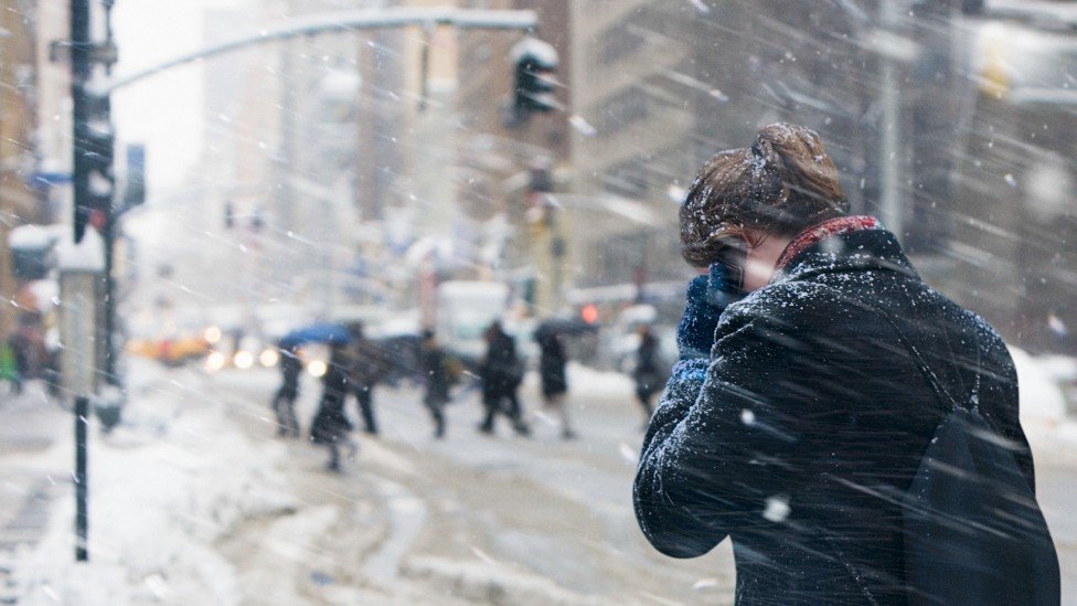 Mulher no celular nos EUA caminha na neve
