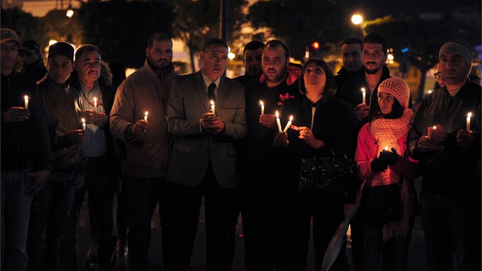 Члены тунисской партии Nidaa Tounes держат свечи во время бдения в Тунисе в память о жертвах взрыва бомбы в автобусе, перевозившем президентскую гвардию Туниса