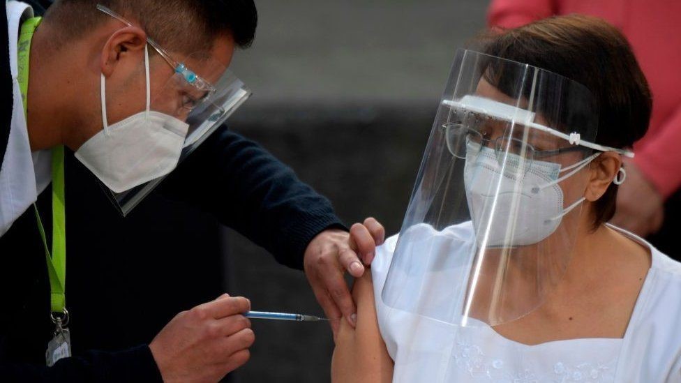 Uma enfermeira mexicana recebendo a vacina