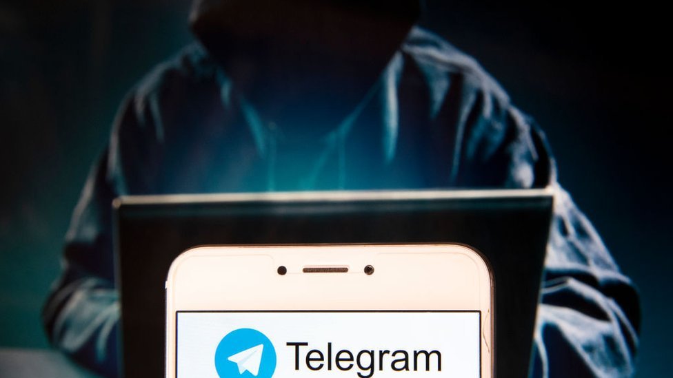 Ilustración de hacker y teléfono con el logo de Telegram.
