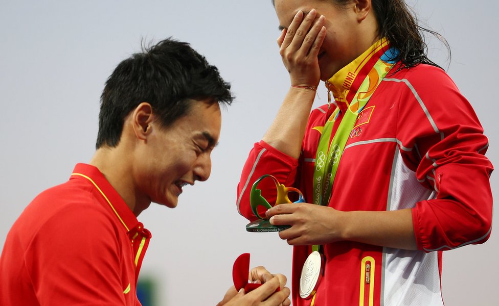 Хе Цзы (CHN) из Китая получает предложение руки и сердца от олимпийского ныряльщика Цинь Кая (CHN) из Китая после церемонии награждения.