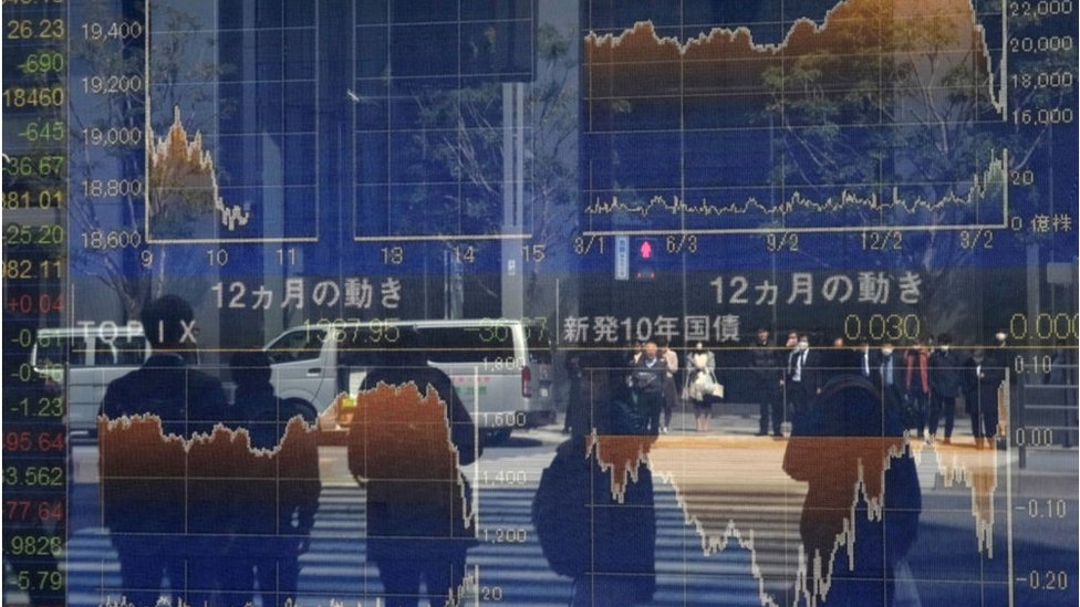 Отражение пешеходов в оконной стойке перед доской для котировок с номерами Токийской фондовой биржи в Токио.