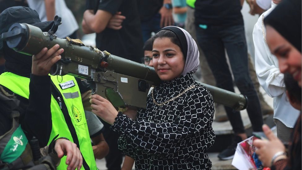 A young Palestinian woman carries an anti-aircraft gun in Gaza City on the third day of the Eid al-Adha holiday (30 June 2023), when Hamas fighters organised a military exhibition under the name 'Resistance, a picture and a souvenir'