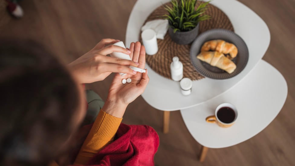 Mulher tomando comprimido no café da manhã