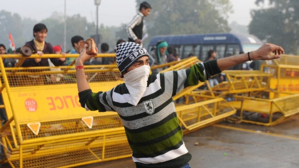 Индийский протестующий бросает камень во время демонстрации