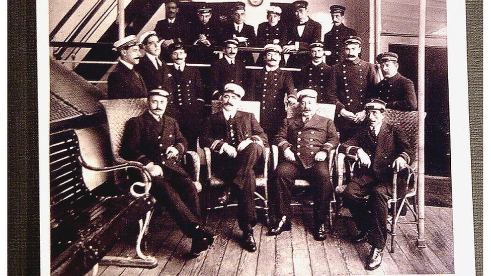 Foto em preto e branco de diversos marinheiros e de capitães com suas roupas de oficial