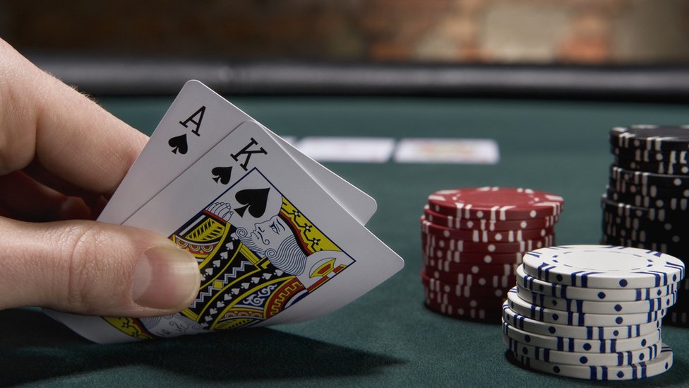 Primer planos de una mano sosteniendo dos cartas de póker durante una partida.