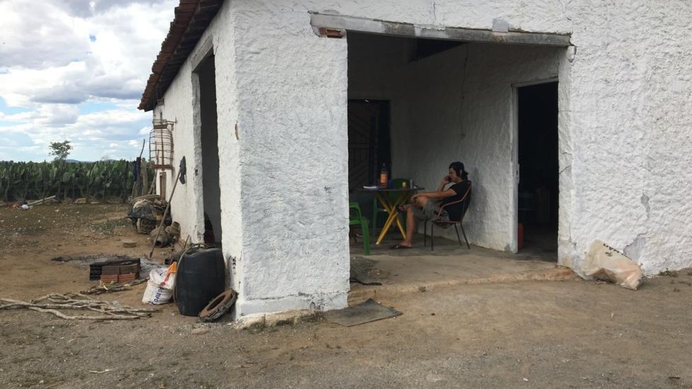 Casa em fazenda de Canudos, com imigrante chinês ao fundo