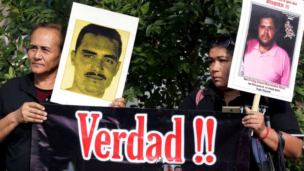 Manifestantes con carteles que muestran el rostro de sus familiares desaparecidos.