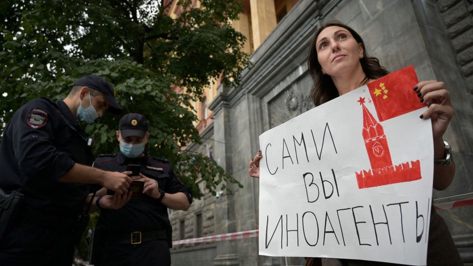Una manifestante sostiene un cartel que dice "agentes extranjeros ustedes".