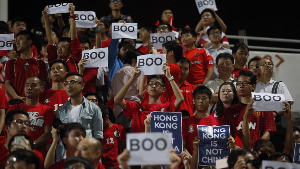 Гонконгские фанаты держат таблички с надписью «Boo», когда во время отборочного турнира чемпионата мира на стадионе Mong Kok в Гонконге 17 ноября 2015 года звучал национальный гимн.