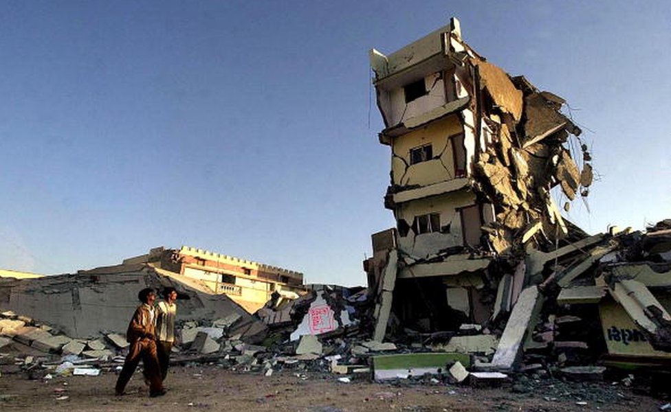 Пара прохожих смотрят на разрушенное здание 29 января 2001 года, где они жили, в городе Бхудж в штате Гуджарат, который вместе со всей северо-западной Индией пострадал от сильного землетрясения 26 января.