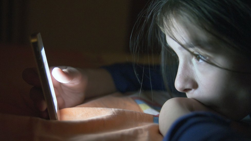 Adolescente frente a una pantalla de celular