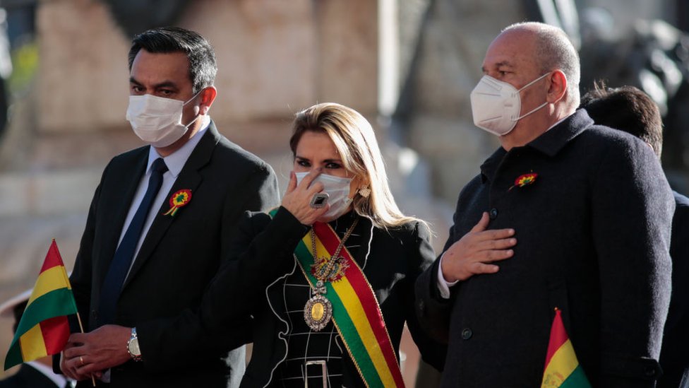 La expresidenta interina de Bolivia, Jeanine Añez, con una mascarilla junto al ministro de Gobierno Arturo Murillo (derecha) y el ministro de la Presidencia, Yerko Núñez (izquierda), durante las celebraciones del Día de la Independencia en medio de la pandemia de coronavirus el 6 de agosto de 2020 en La Paz. Bolivia.