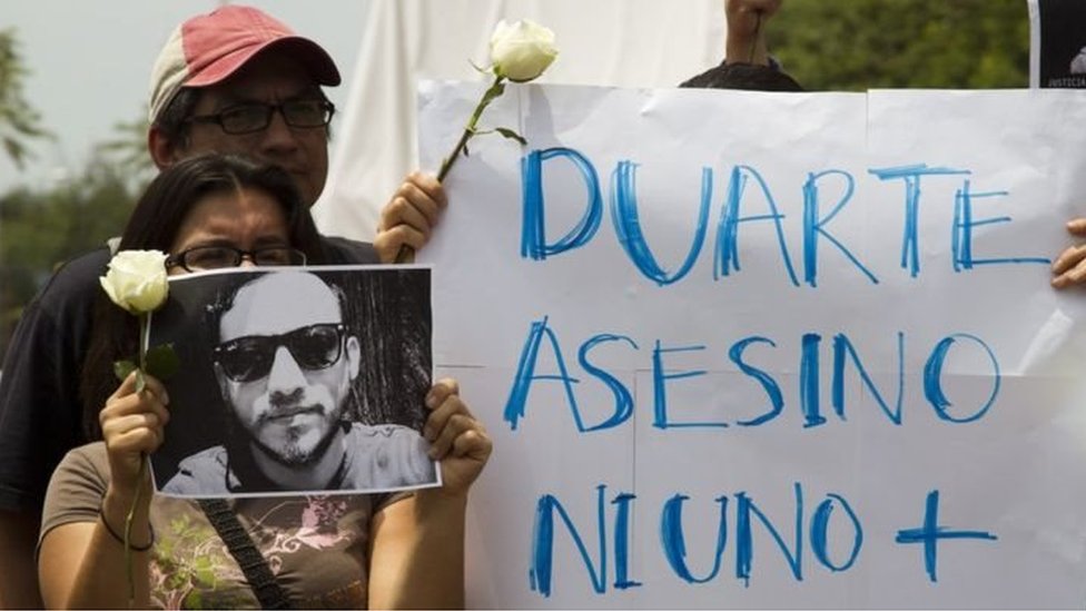 Протестующие держат табличку с надписью« Убийца Дуарте, ни один больше »