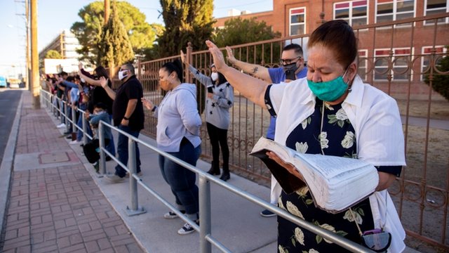 Personas con los brazos en alto rezan a las puertas del Centro Méidco de la Universidad de el Paso.