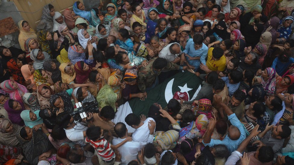 Люди окружают труп пакистанского солдата, предположительно убитого индейскими выстрелами, во время похорон в Фейсалабаде, Пакистан, в четверг, 29 сентября 2016 г.