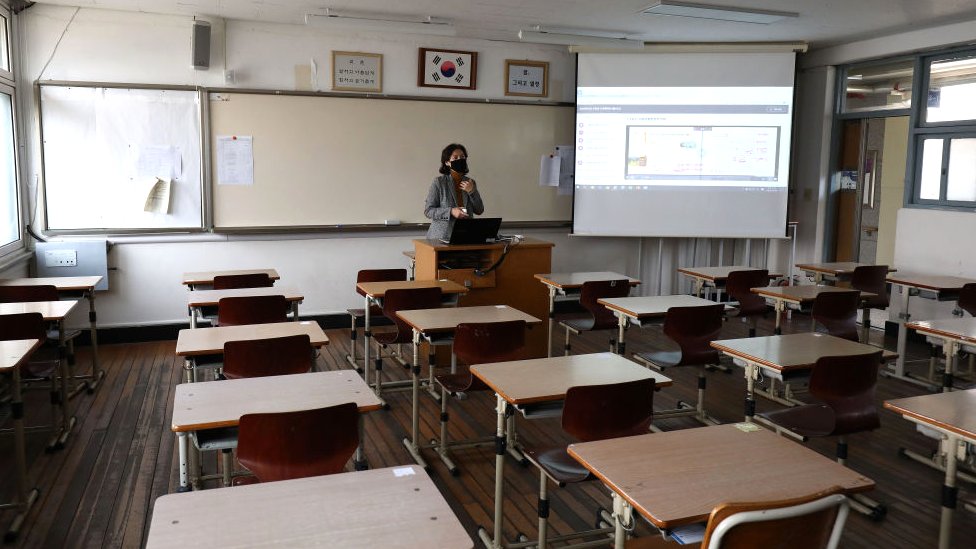 Учительница в маске дает урок в первый день онлайн-занятий в пустом классе