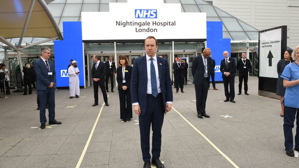 Министр здравоохранения Мэтт Хэнкок и сотрудники NHS стоят на отметках на земле, созданных для обеспечения соблюдения правил социального дистанцирования, на открытии NHS Nightingale Hospital в центре ExCel в Лондоне