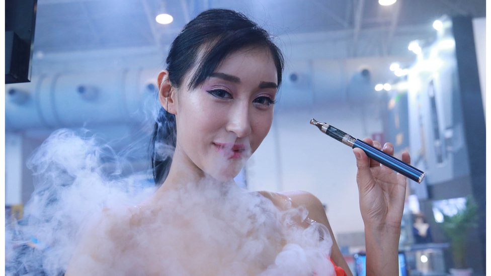 Модель курит электронную сигарету во время выставки Beijing International Vapor Distribution Alliance Expo