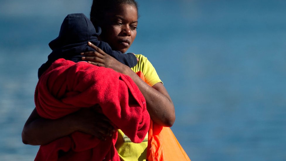 Mujer cargando a un niño migrante.