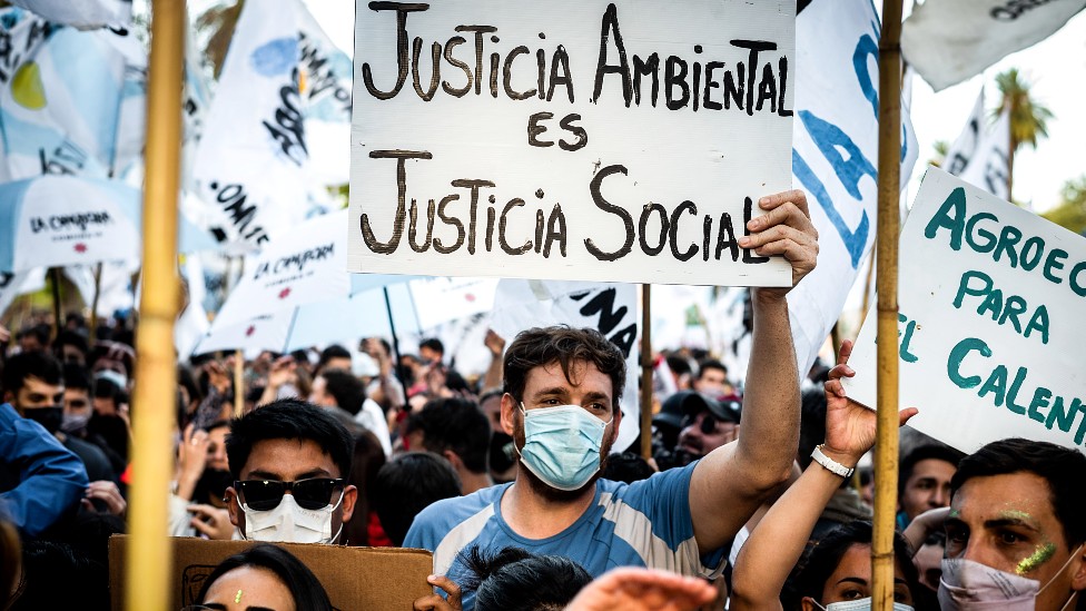 Jóvenes con un cartel que dice "justicia ambiental es justicia social".