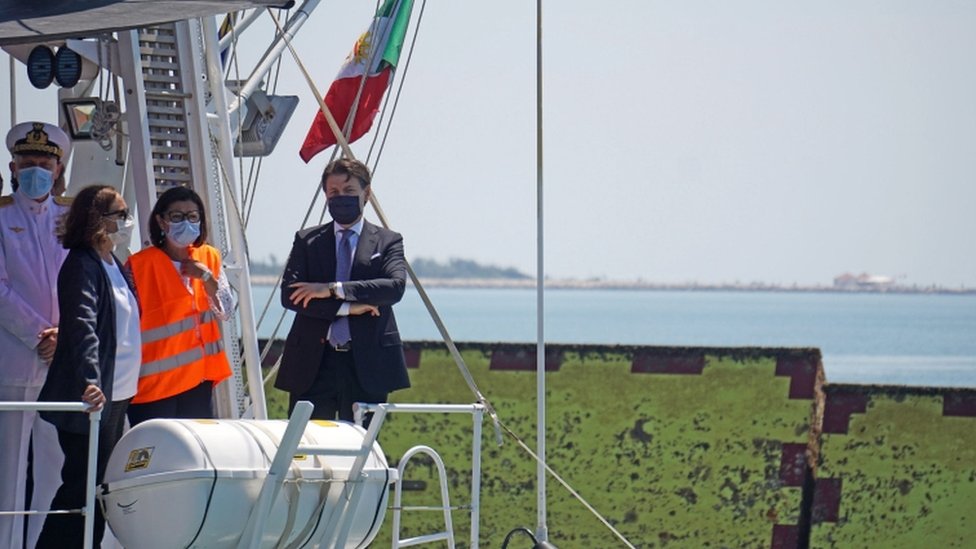 Премьер-министр Италии Джузеппе Конте стоит на палубе лодки итальянской береговой охраны