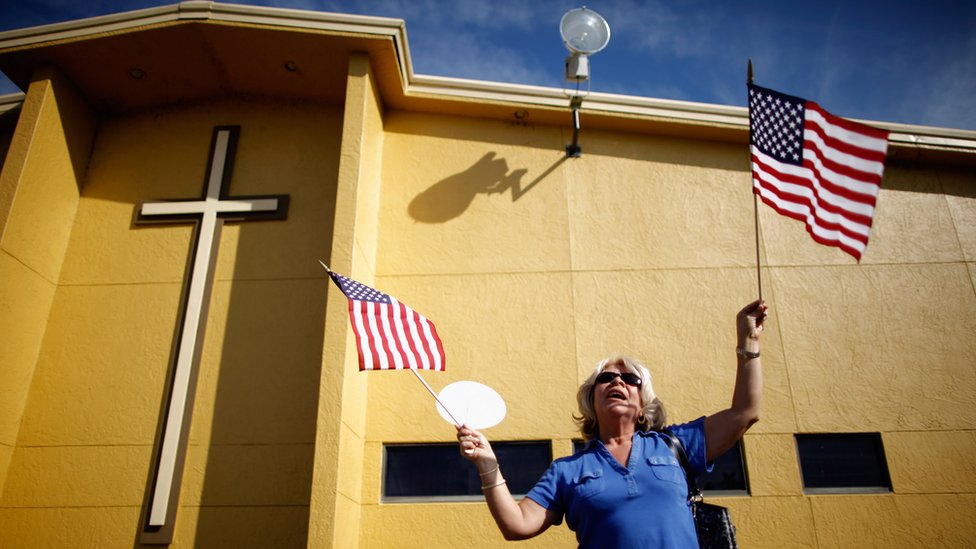 Женщина держит американские флаги у евангелической церкви Centro de la Familia 28 января 2012 года в Орландо, Флорида.