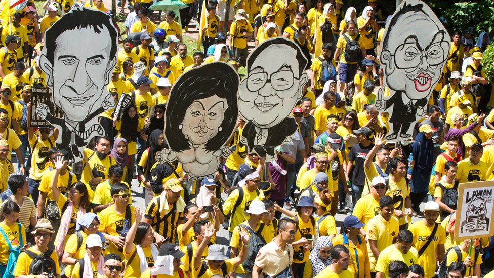 Протестующие в желтых рубашках в Куала-Лумпуре держат карикатуры