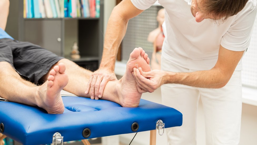 Un médico revisando la sensibilidad de un pie.