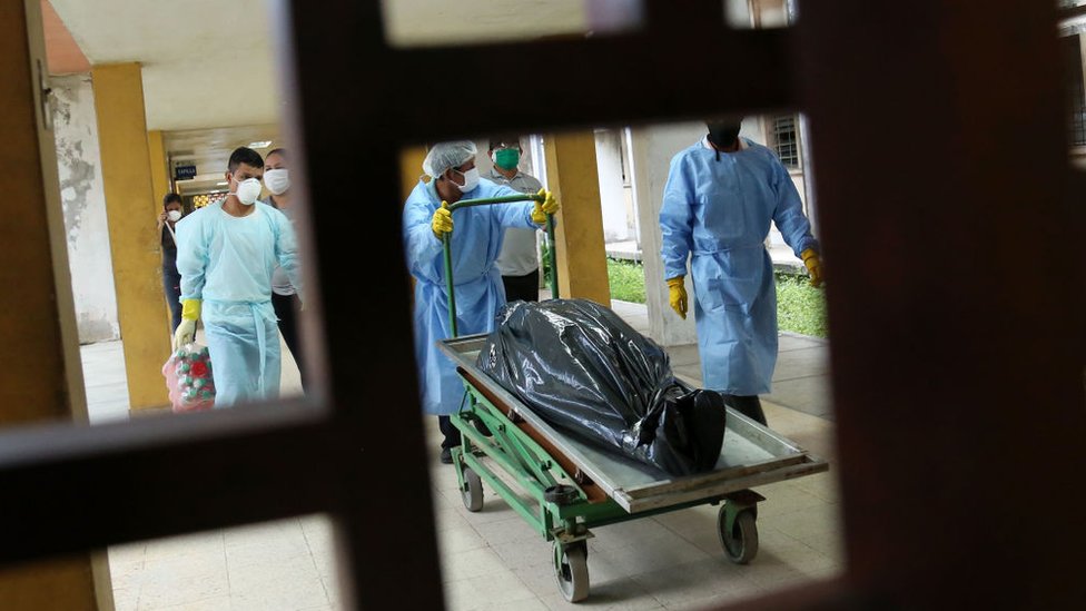 Médicos trasladando a un fallecido envuelto en plástico en el Hospital Regional de Loreto.