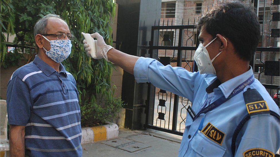 Житель проходит тепловую проверку в жилом комплексе во время общенациональной блокировки из-за коронавируса в Гуруграме