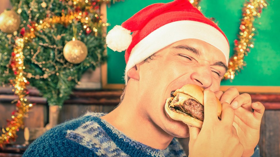 Hombre comiendo con un gorro navideño