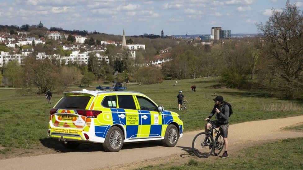 A man is told by a police officer that there is no cycling at Parliament Hill Viewpoint in Hampstead Heath on April 04, 2020 in London, England.