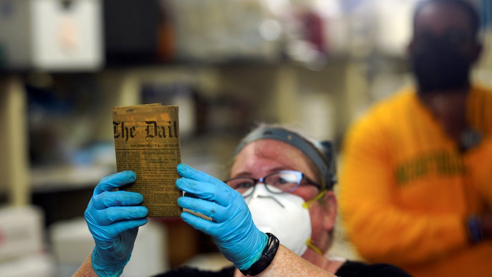 Integrante da equipe de preservação do Departamento de Recursos Históricos da Virgínia mostra item da 'cápsula do tempo'