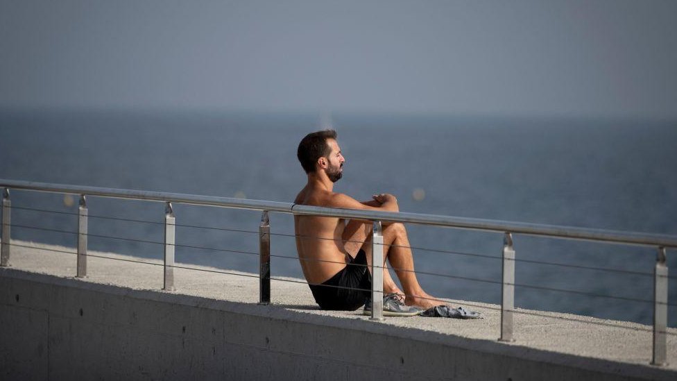 A man enjoys the sun in Barceloneta beach, in Barcelona on October 27, 2022.