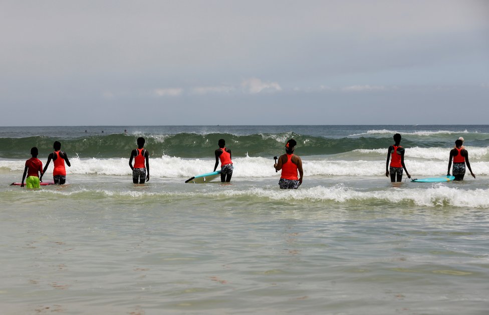 Khadjou Sambe teaches girls and women surfing techniques in the sea