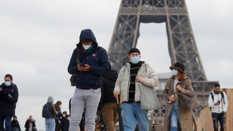 Personas, con mascarillas protectoras, caminan por la plaza Trocadero, cerca de la Torre Eiffel en París.