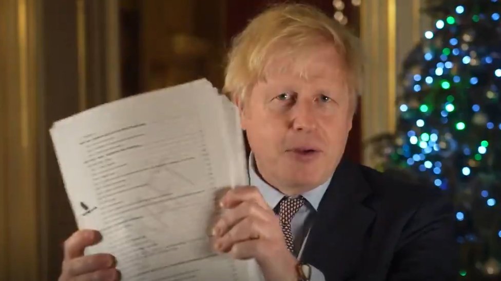 Boris Johnson holds up a draft of the Brexit deal document in video message on Christmas Eve 2020