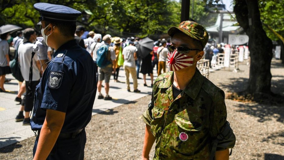 Un hombre con una máscara protectora con la bandera del Sol Naciente en Tokio agosto de 2020.