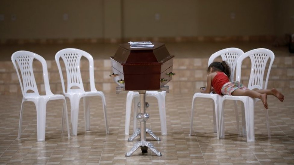 A relative of murdered prisoner lies on a chair next to a coffin during a wake after a prison riot in the city of Altamira, Para state, Brazil July 30, 2019.