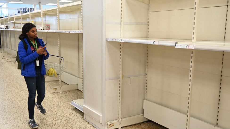 Покупатель смотрит на пустые полки в отделении для рулонов туалетной бумаги в магазине на севере Лондона, Великобритания, 12 марта 2020 года. Число случаев коронавируса в Великобритании продолжает расти, а десять человек уже умерли из-за вспышки коронавируса.