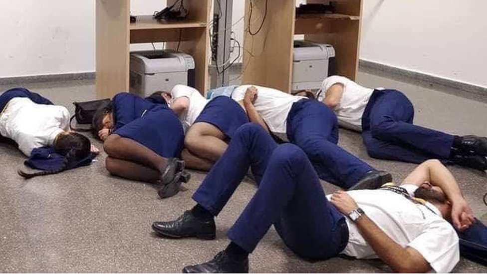 Seis personas con uniformes de Ryanair duermen en el suelo de una oficina del aeropuerto de Málaga, España.